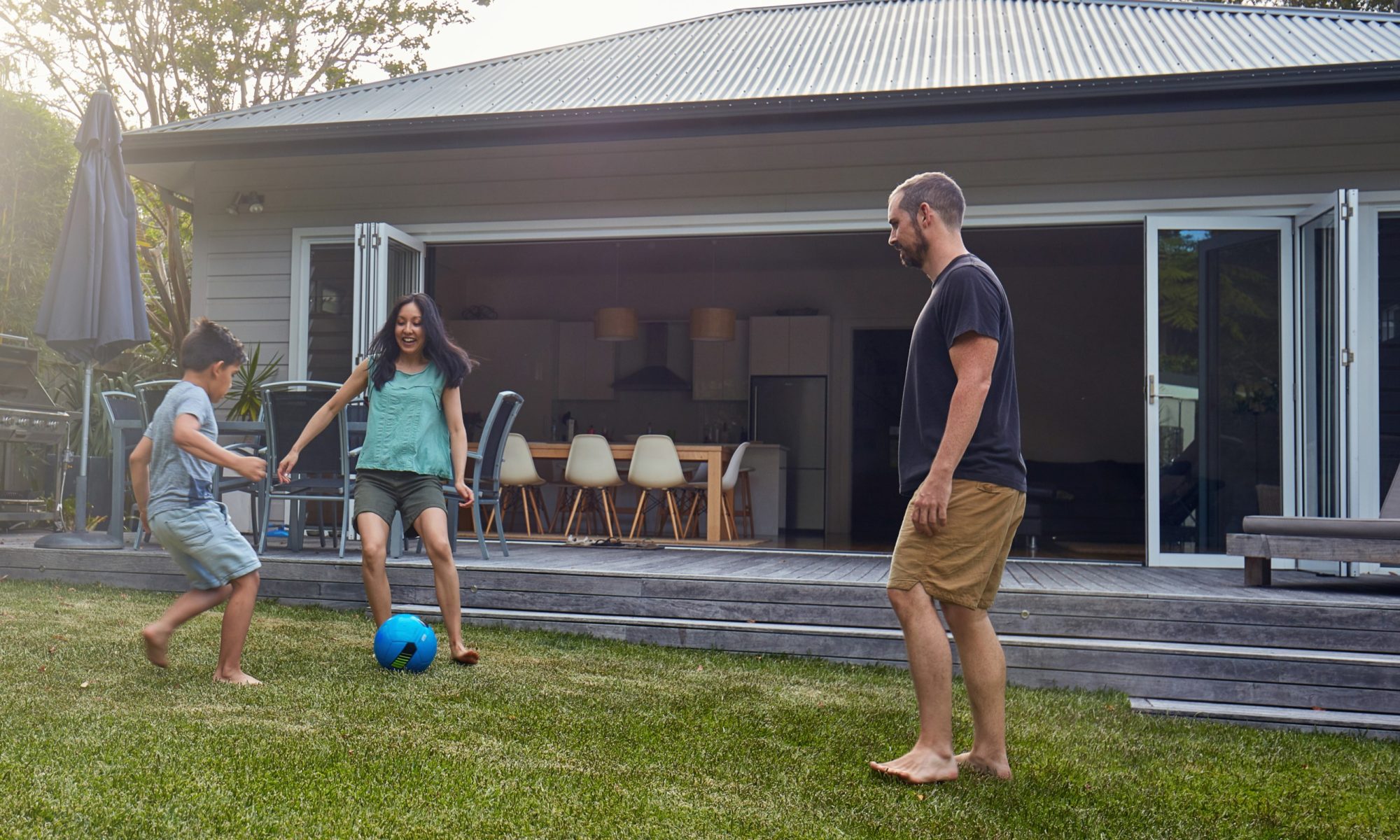 Young family kicking ball in backyard